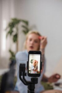 1. A woman captures a selfie with her phone, showcasing her vibrant personality for an influencer marketing agency. 2. A woman takes a selfie with her phone, embodying the essence of influencer marketing for her audience. 3. A woman smiles as she takes a selfie with her phone, representing the dynamic world of influencer marketing.